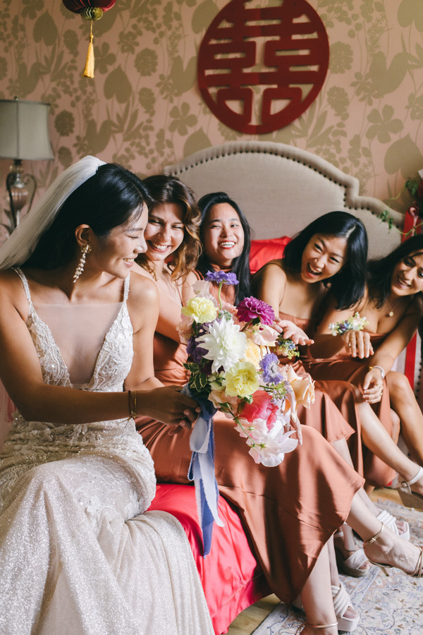 Mariée entourée de ses demoiselles d’honneur riant ensemble pendant les préparatifs du mariage