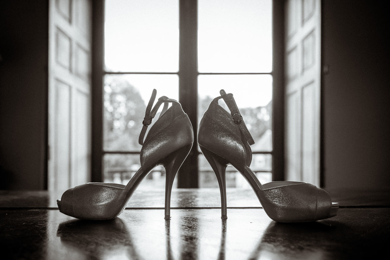 Chaussures de la mariée posées devant une fenêtre pendant les préparatifs du mariage