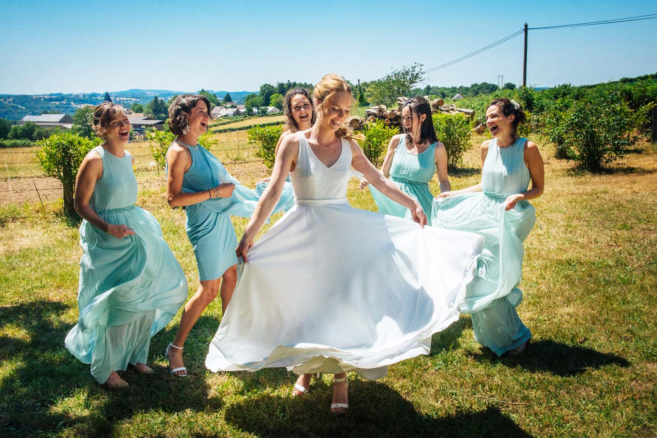 Mariée entourée de ses demoiselles d’honneur dans un champ lors d’un mariage en Bourgogne