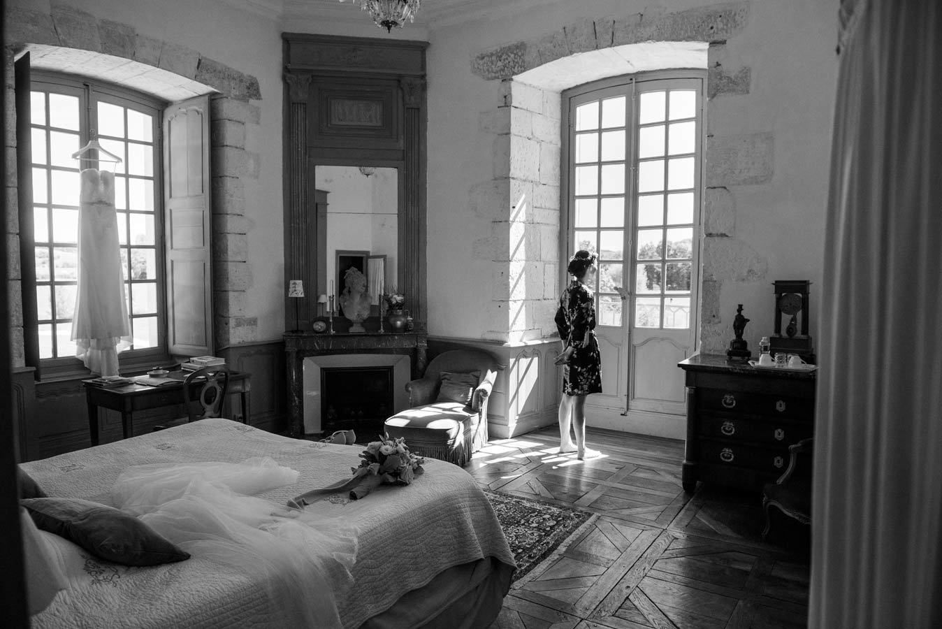 Chambre lumineuse dans l'Abbaye de Reigny en Bourgogne avec la robe de mariée suspendue pendant les préparatifs du mariage