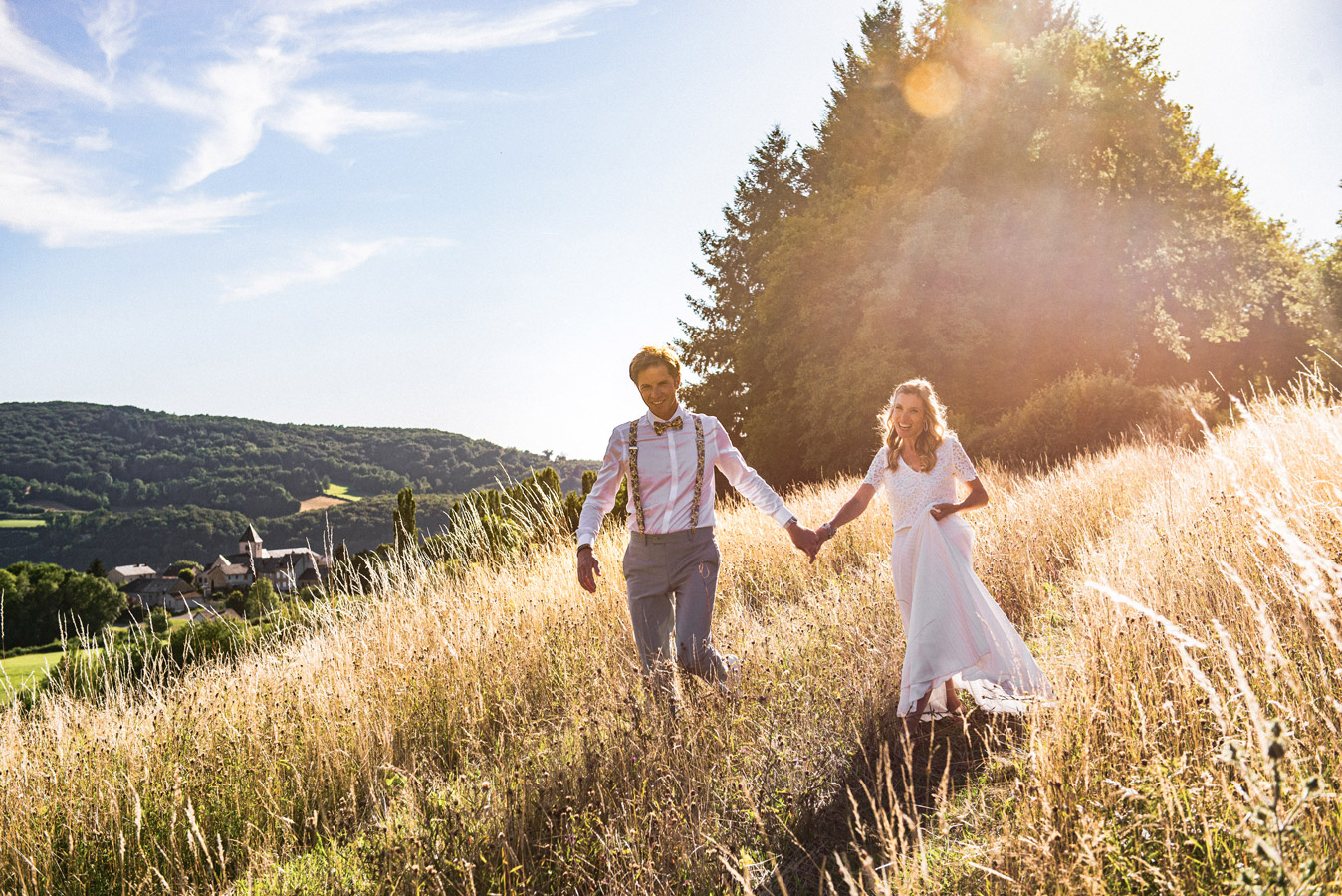 Couple de mariés marchant main dans la main dans les champs au coucher du soleil près d’Auxerre en Bourgogne