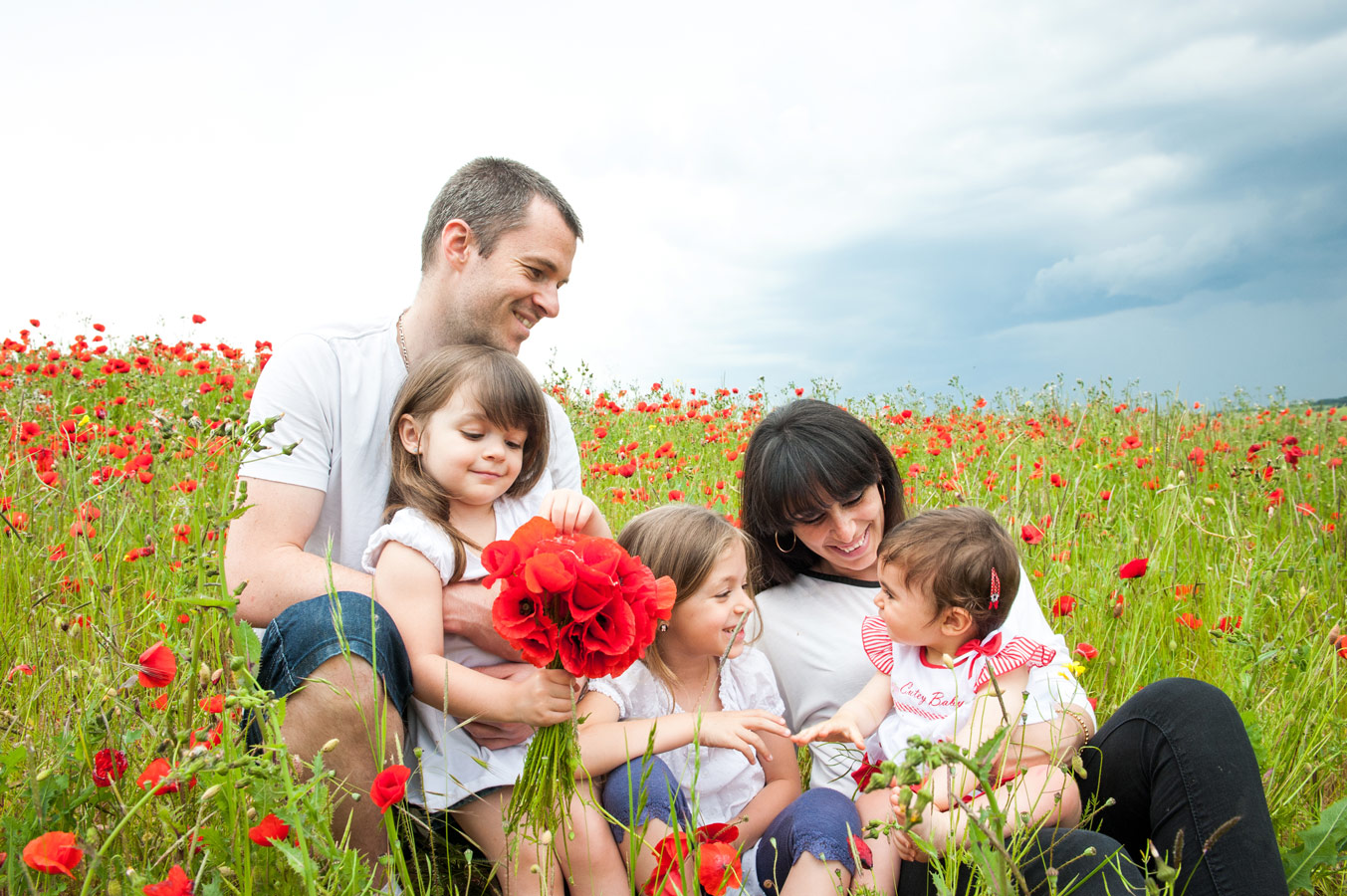 Famille avec trois enfants assise dans un champ de coquelicots lors d’une séance photo famille en Bourgogne