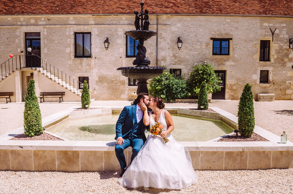 Couple de mariés s'embrassant devant la fontaine au Domaine de Colombiers